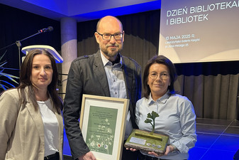 Dwie kobiety oraz mężczyzna trzymający w ręku statuetkę w kształcie liścia oraz ramkę z nagrodą.